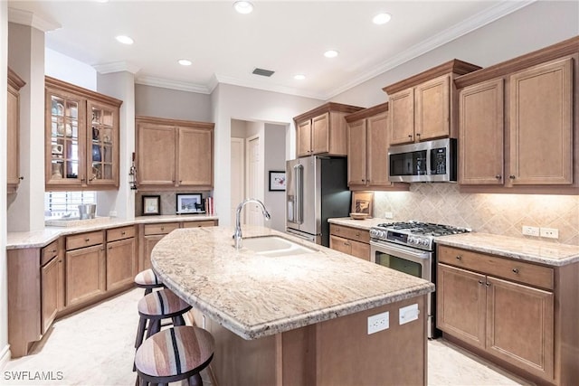 kitchen with tasteful backsplash, a kitchen bar, sink, a kitchen island with sink, and stainless steel appliances