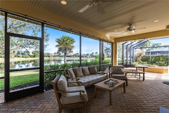 sunroom / solarium featuring ceiling fan and a water view