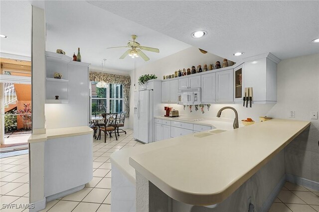 kitchen featuring white appliances, kitchen peninsula, light tile patterned floors, white cabinets, and ceiling fan