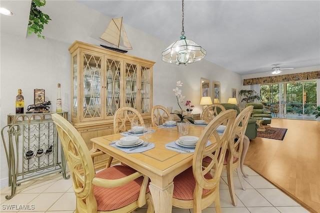 tiled dining space featuring ceiling fan with notable chandelier