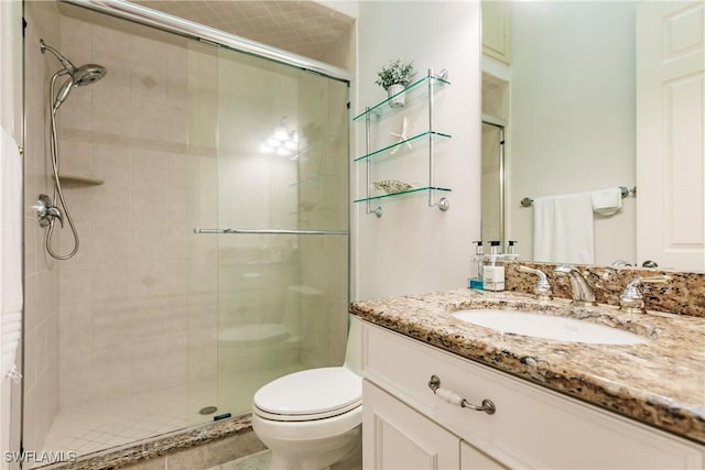 bathroom featuring vanity, toilet, and a shower with door