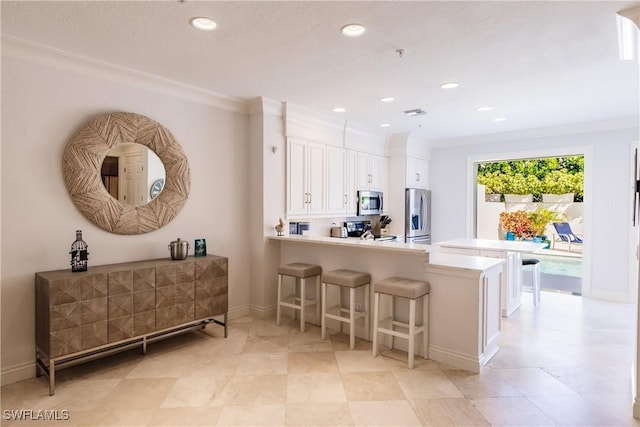 kitchen featuring appliances with stainless steel finishes, white cabinets, a kitchen breakfast bar, and kitchen peninsula