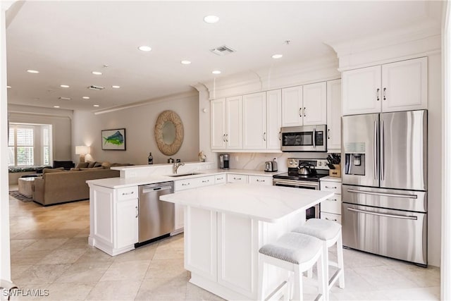 kitchen featuring sink, appliances with stainless steel finishes, a kitchen breakfast bar, a kitchen island, and kitchen peninsula