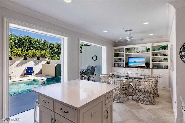 kitchen featuring white cabinetry, a center island, ceiling fan, and crown molding