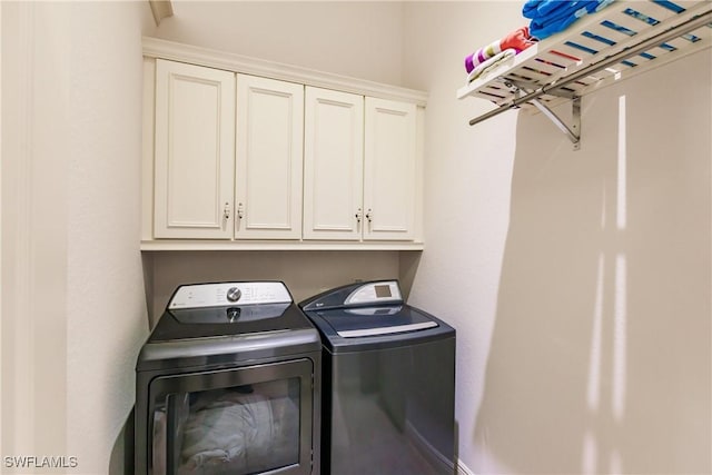 clothes washing area with cabinets and washer and dryer