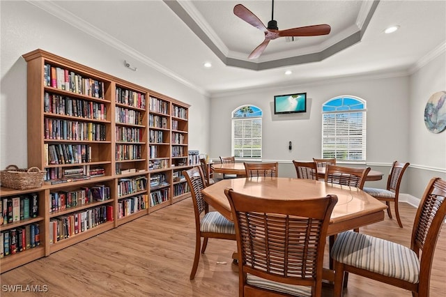 dining room with ceiling fan, crown molding, light hardwood / wood-style flooring, and a tray ceiling