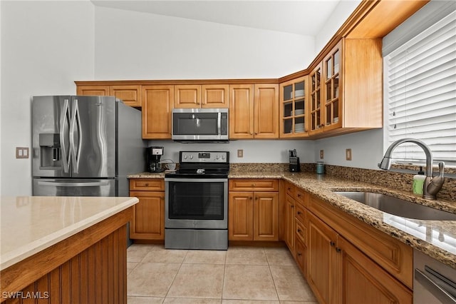 kitchen featuring light tile patterned floors, sink, light stone counters, and stainless steel appliances