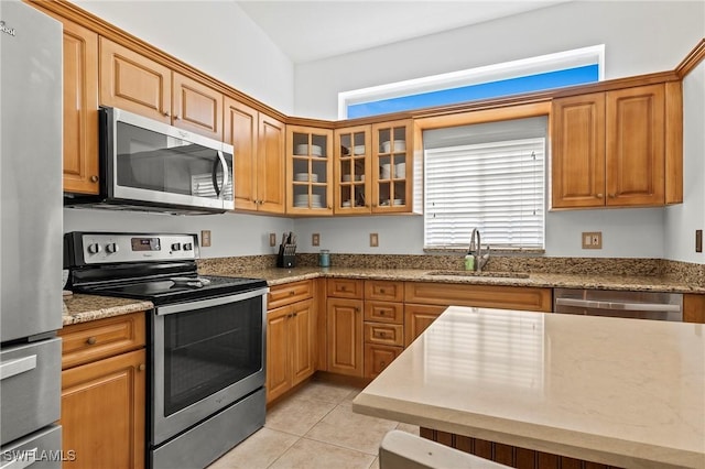 kitchen with sink, light stone counters, stainless steel appliances, and light tile patterned flooring