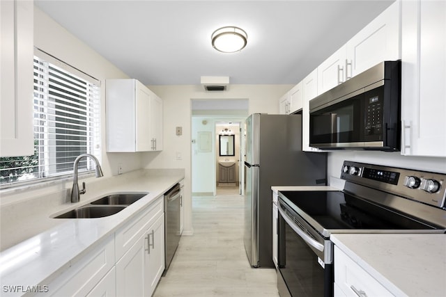 kitchen featuring appliances with stainless steel finishes, white cabinetry, a wealth of natural light, and sink