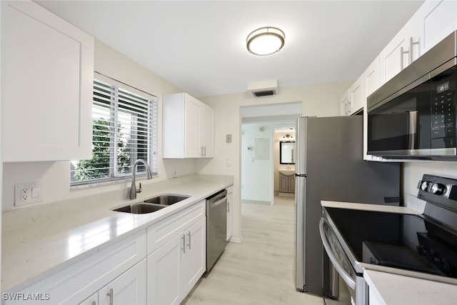 kitchen featuring white cabinets, appliances with stainless steel finishes, light stone counters, and sink