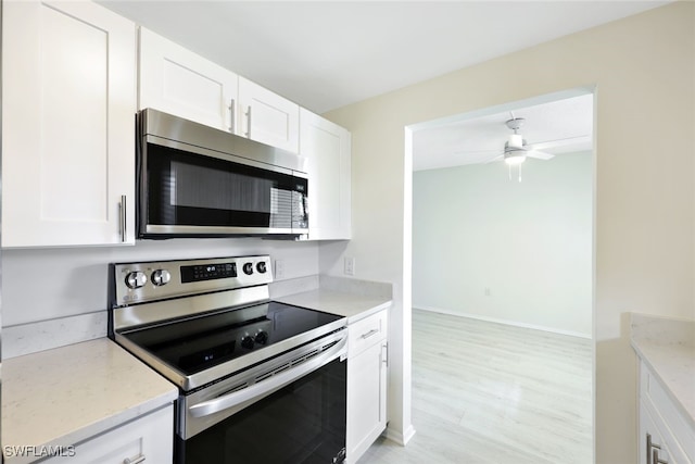 kitchen with white cabinets, appliances with stainless steel finishes, and light stone counters