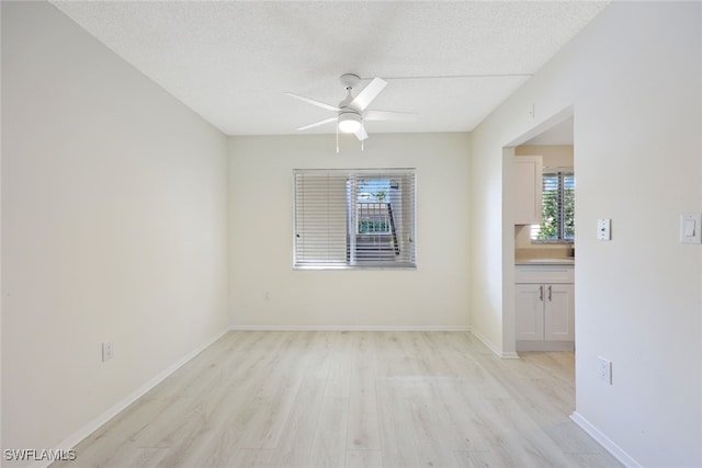 spare room with ceiling fan, light hardwood / wood-style floors, and a textured ceiling