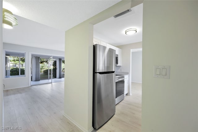 kitchen featuring white cabinetry, stainless steel appliances, a textured ceiling, and light wood-type flooring