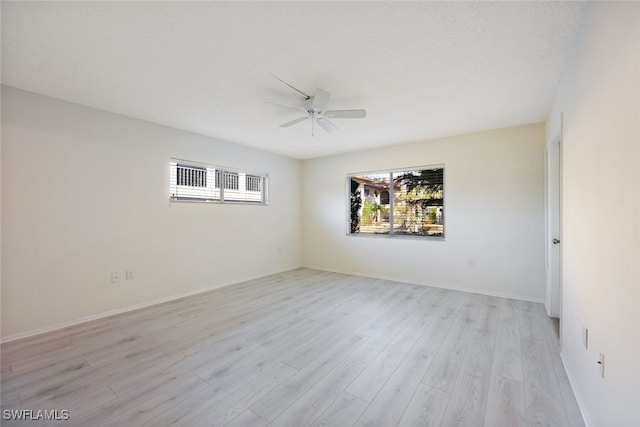 empty room with a textured ceiling, light hardwood / wood-style flooring, and ceiling fan