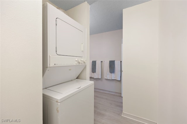 clothes washing area with a textured ceiling, light hardwood / wood-style floors, and stacked washer and clothes dryer