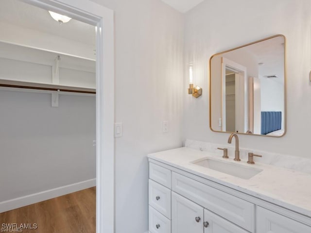 bathroom with wood finished floors, vanity, and baseboards