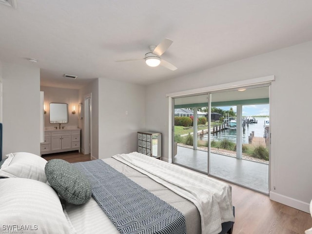 bedroom with access to exterior, visible vents, a sink, wood finished floors, and baseboards