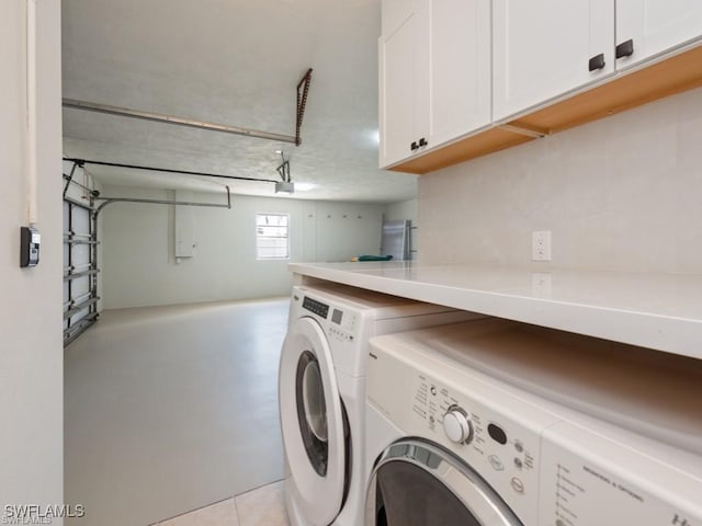 clothes washing area featuring a garage, cabinet space, and washer and dryer