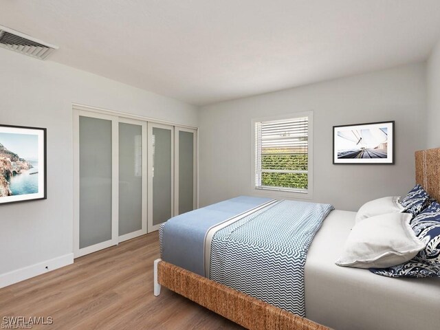 bedroom featuring light wood-type flooring, baseboards, visible vents, and a closet