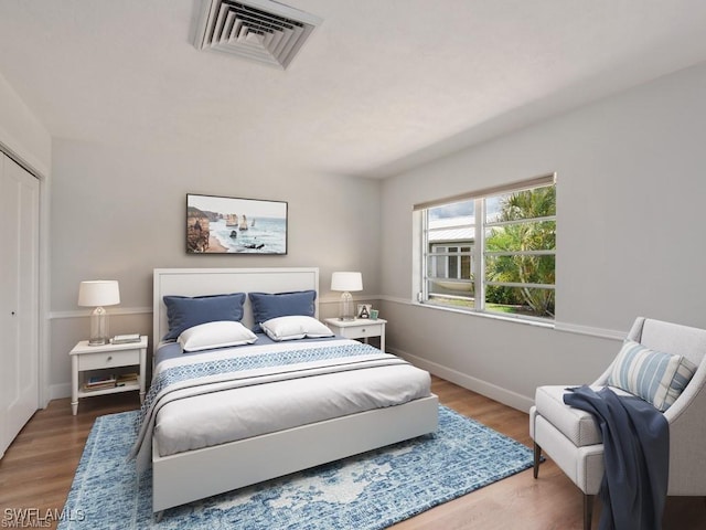 bedroom featuring baseboards, visible vents, and wood finished floors