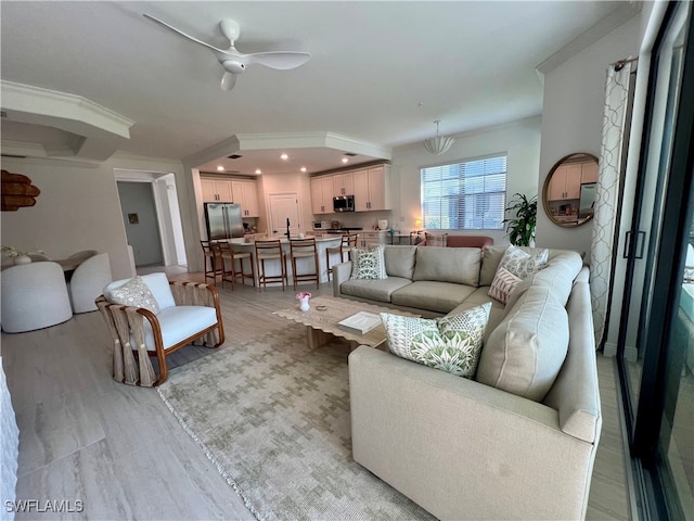 living room featuring ceiling fan, ornamental molding, and light hardwood / wood-style floors