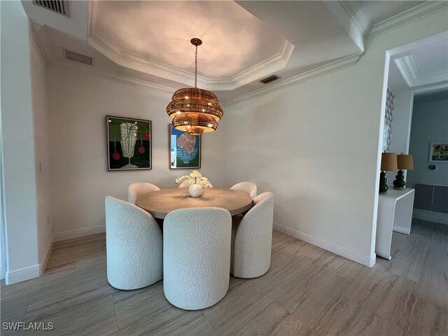 dining area with crown molding, a notable chandelier, and a tray ceiling