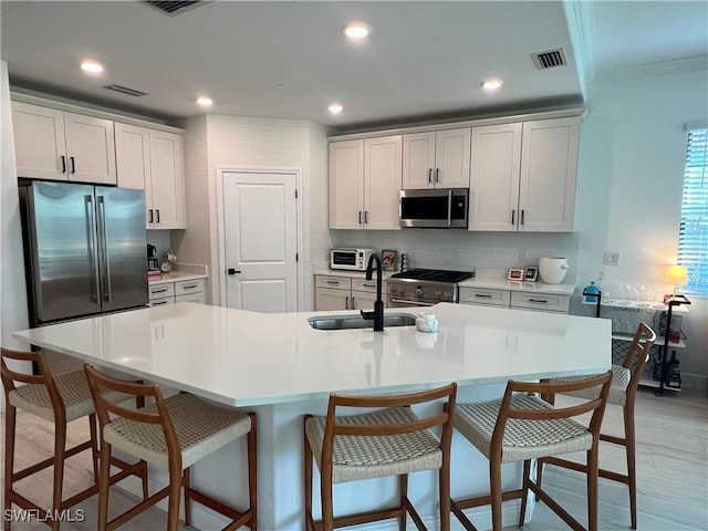 kitchen with white cabinets, a kitchen island with sink, sink, and stainless steel appliances