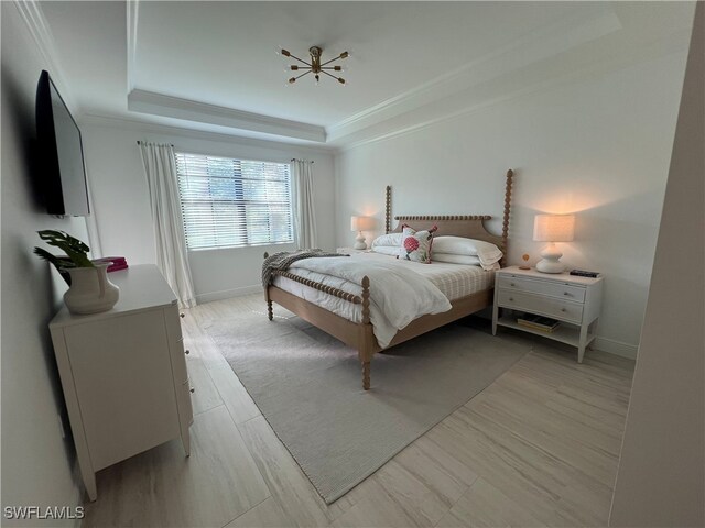 bedroom with ornamental molding, light hardwood / wood-style flooring, and a tray ceiling