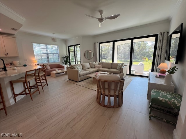 living room featuring ceiling fan, crown molding, and plenty of natural light