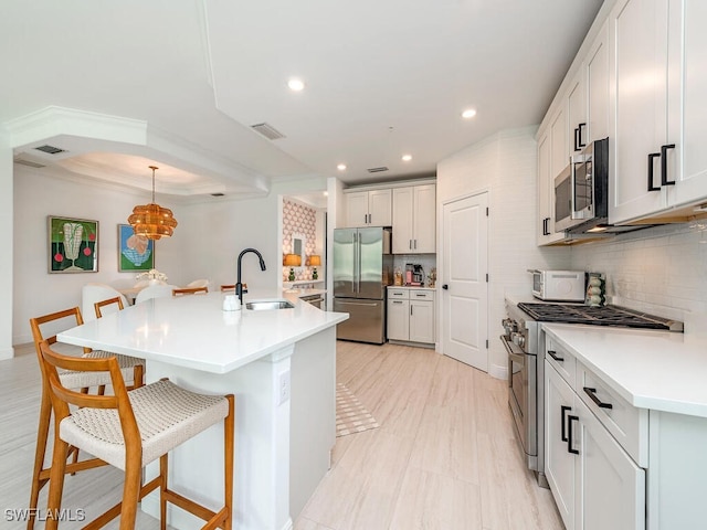 kitchen with tasteful backsplash, a kitchen island with sink, a kitchen breakfast bar, high quality appliances, and white cabinets