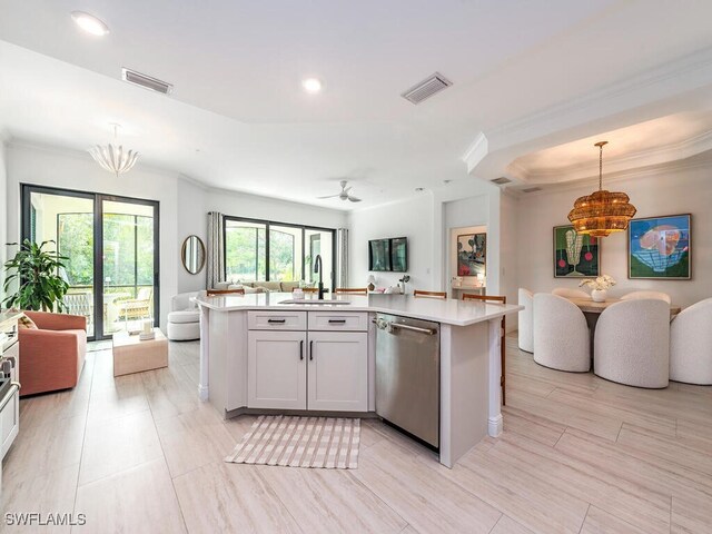 kitchen featuring decorative light fixtures, white cabinets, dishwasher, and sink