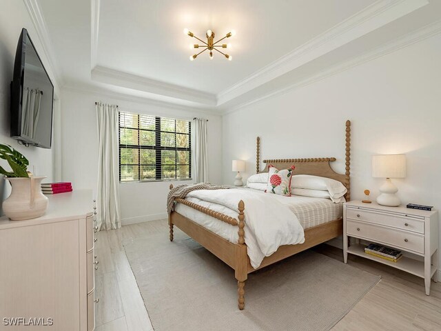 bedroom featuring crown molding, a raised ceiling, and light wood-type flooring