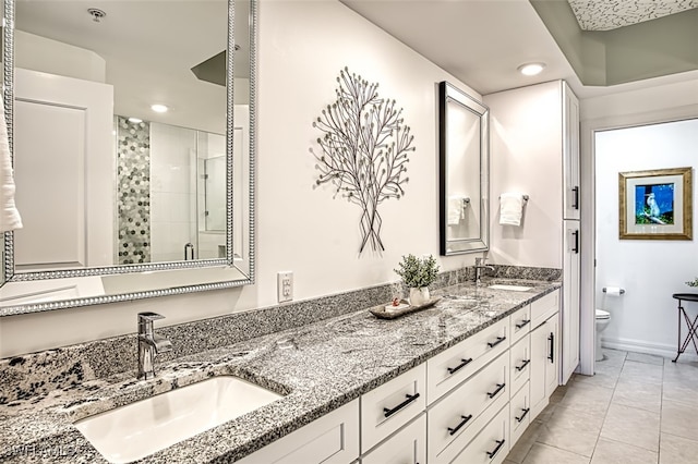 bathroom featuring double vanity, a stall shower, a sink, and toilet