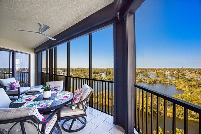 sunroom / solarium featuring ceiling fan and a water view