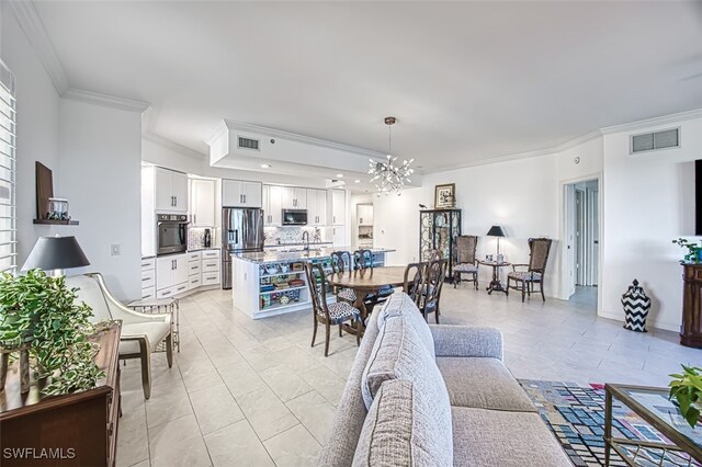 living room featuring light tile patterned floors, ornamental molding, a chandelier, and sink