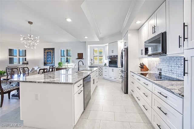 kitchen with white cabinets, decorative backsplash, a kitchen island with sink, stainless steel appliances, and a sink