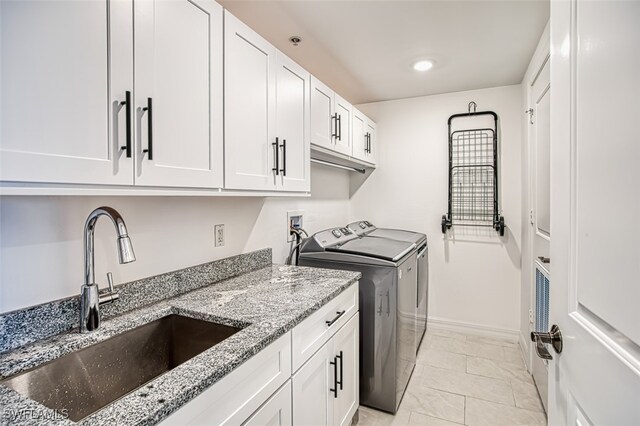 washroom featuring washer and dryer, light tile patterned flooring, sink, and cabinets