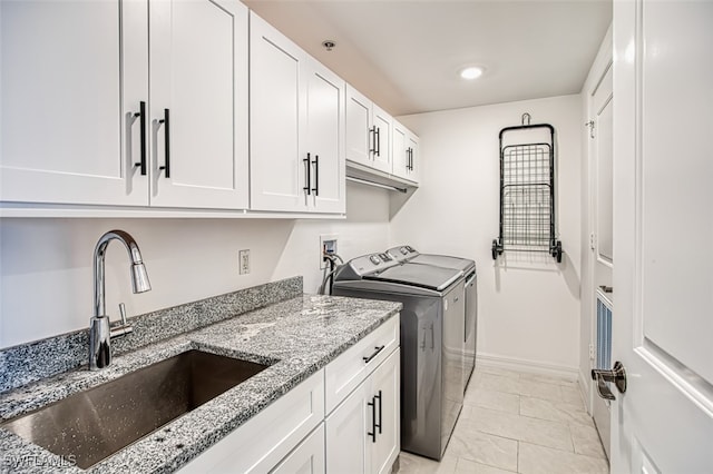 laundry room featuring separate washer and dryer, a sink, cabinet space, and baseboards