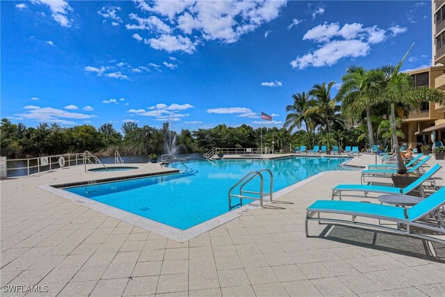 view of swimming pool featuring a hot tub and a patio area