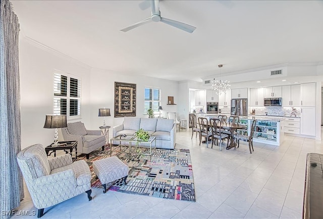 living room with ceiling fan with notable chandelier, light tile patterned floors, and ornamental molding