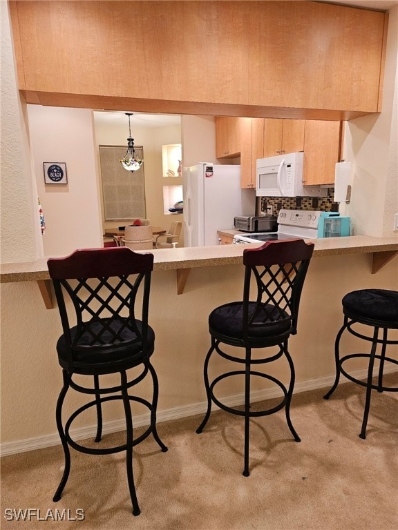 kitchen with white appliances, kitchen peninsula, decorative light fixtures, and a kitchen breakfast bar