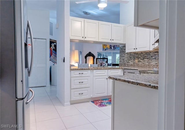 kitchen with kitchen peninsula, light stone countertops, light tile patterned floors, white cabinetry, and stainless steel refrigerator