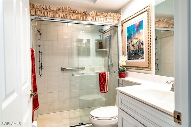 bathroom featuring vanity, a shower with shower door, and toilet