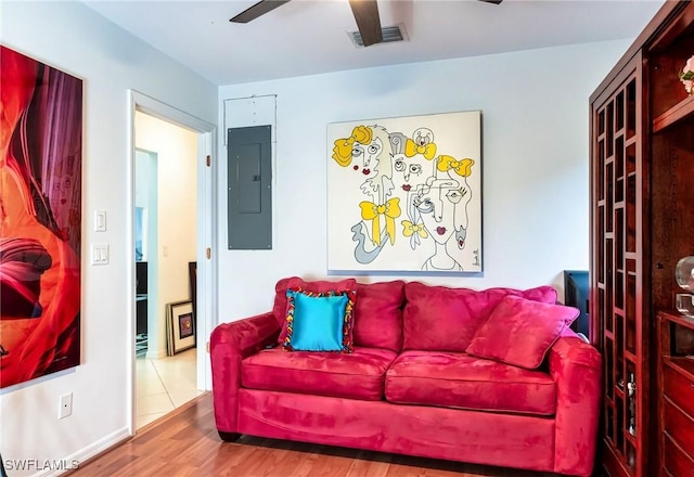 living room with electric panel, ceiling fan, and hardwood / wood-style floors