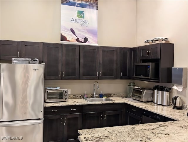 kitchen featuring sink, light stone counters, and stainless steel appliances