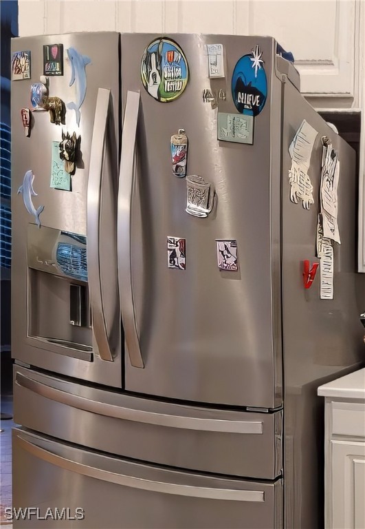 details featuring stainless steel refrigerator with ice dispenser and white cabinetry