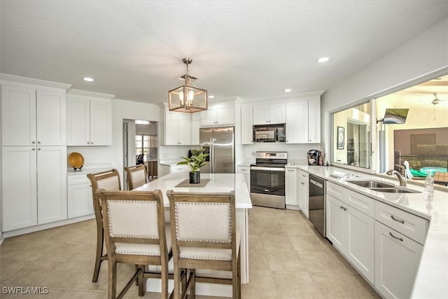 kitchen featuring stainless steel appliances, sink, decorative light fixtures, a center island, and a kitchen breakfast bar