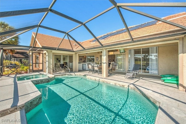 view of pool featuring a patio, glass enclosure, and an in ground hot tub