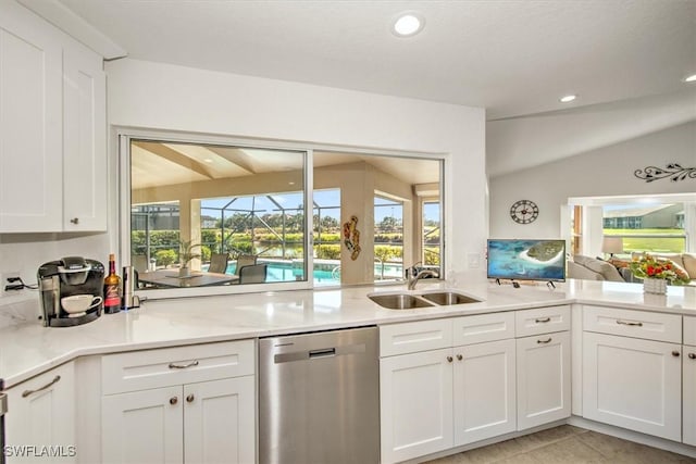 kitchen featuring vaulted ceiling, dishwasher, light tile patterned floors, white cabinets, and sink