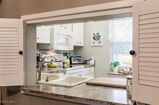 kitchen with backsplash, white appliances, white cabinetry, and sink